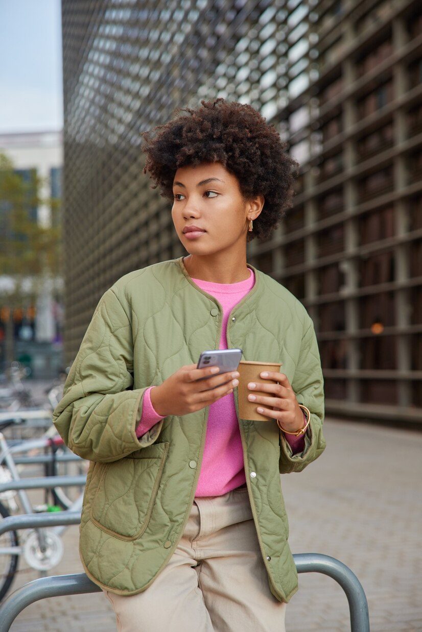 Freelancer smiling at her phone with a cup in hand